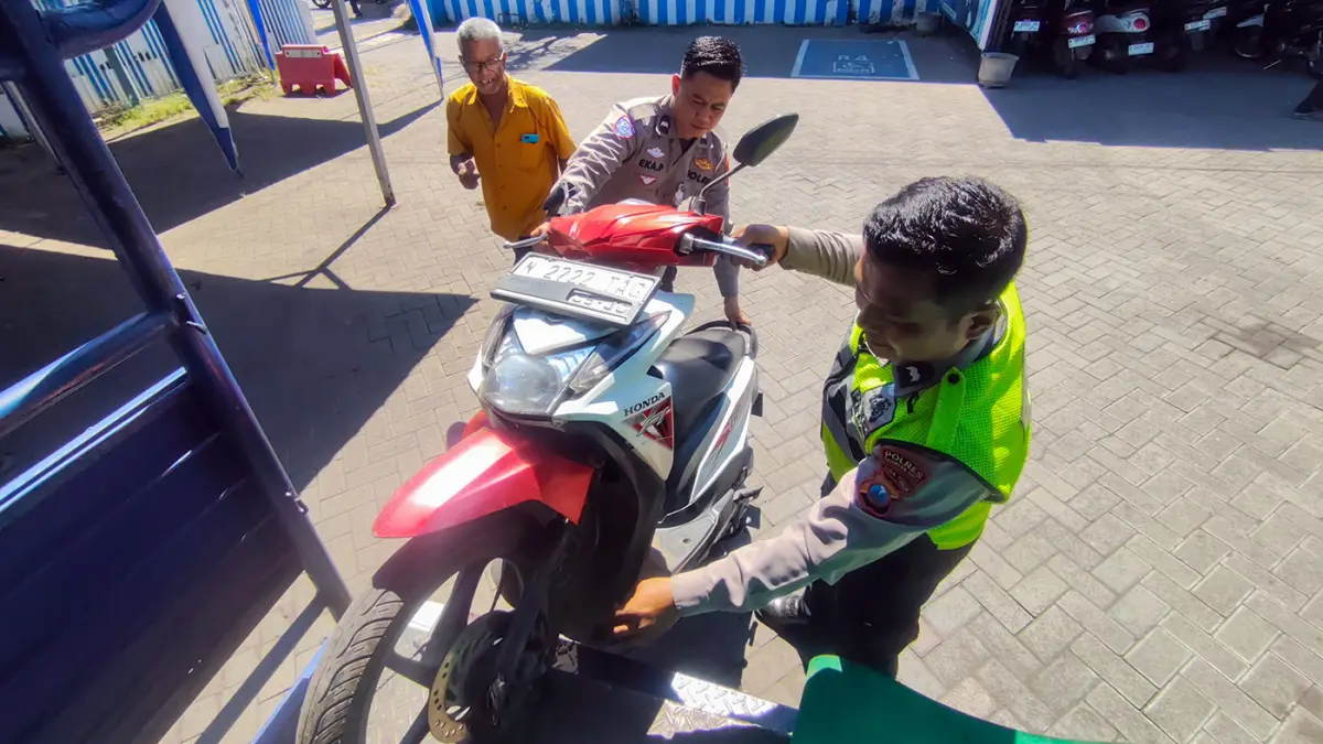 BARANG BUKTI: Petugas Unit Laka Satlantas Polres Pasuruan Kota mengamankan motor korban kecelakaan maut, Kamis (11/6) pagi di Jl. A Yani, Kelurahan/ Kecamatan Gadingrejo, Kota Pasuruan. Dua kakak-adik meninggal setelah motornya jatuh dan terlindas truk. (Mokhamad Zubaidillah/ Radar Bromo)
