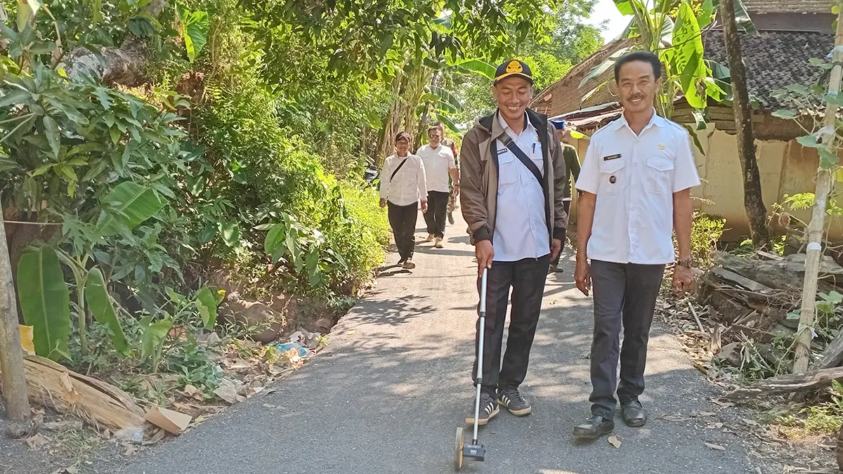 UKUR JALAN: Kepala Desa Gunggungan Kidul Suhdi mendampingi tim monev dari Pemerintah Kecamatan Pakuniran, mengukur hasil pengaspalan jalan di Dusun Dulukan RT 4/RW 2. (DIDIK PURWANTO/JAWA POS RADAR BROMO)
