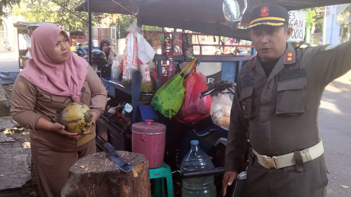 BERI PERINGATAN: Petugas Satpol PP saat melakukan sosialsiasi pada para PKL agar tak jualan di kawasan Stadion Bayuangga selama konser Denny Caknan, Sabtu besok (13/6).  