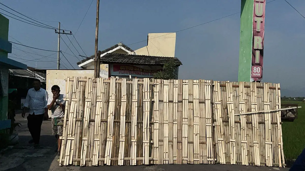 TUTUPI JALAN MASUK: Gedek yang dipasang di depan gerbang perumahan Grand City di Desa Sidopekso, Kraksaan hingga menutup jalan perumahan. &nbsp;(Foto: Agus Faiz Musleh/Jawa Pos Radar Bromo)