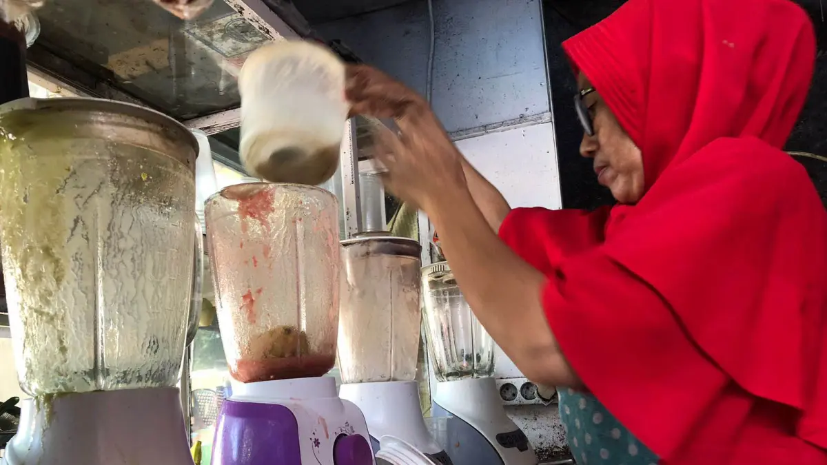 SEMANGAT: Eni, warga Kelurahan Mangunharjo, Kecamatan Mayangan saat melayani pembelian es jus di warungnya, Jumat (19/6) siang. (Foto: Inneke Agustin/Jawa Pos Radar Bromo)
