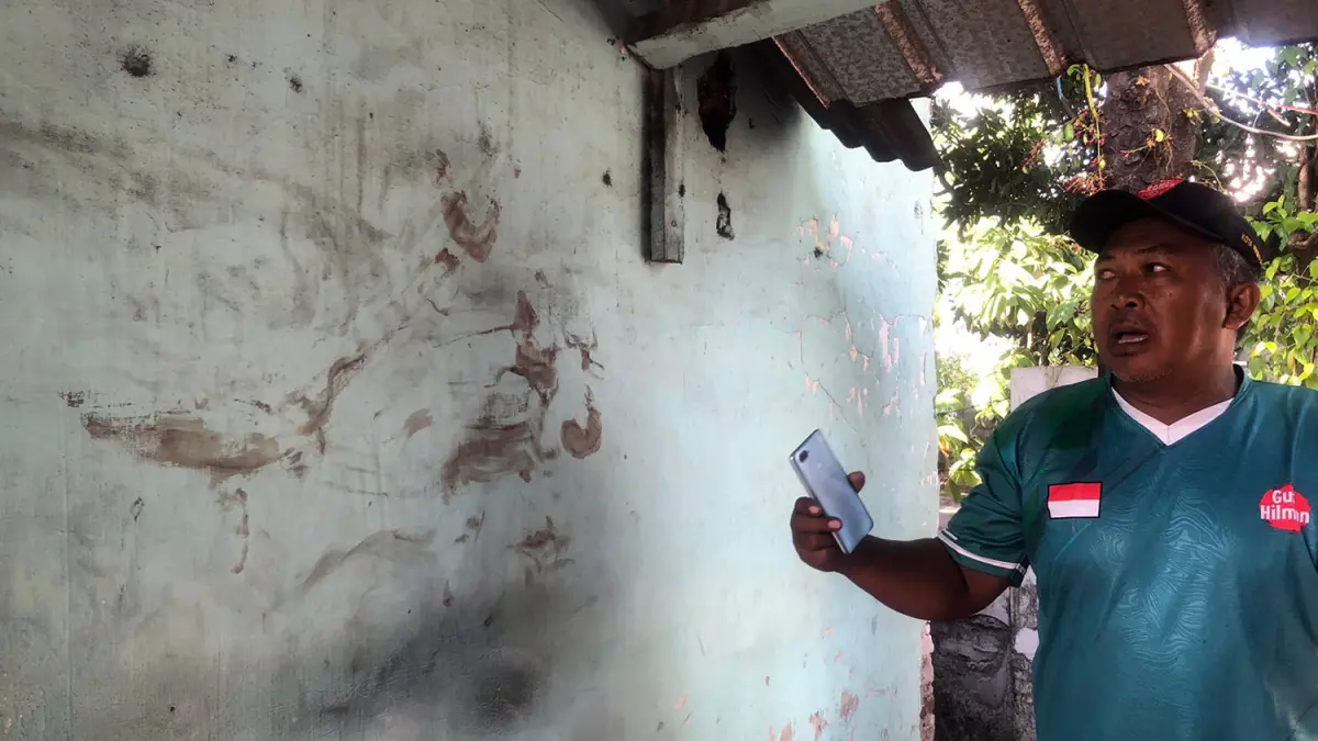 NODA DARAH: Adi menunjukkan noda darah di dinding tak jauh dari ditemukannya manusia silver yang alami luka di kepala. (Inneke Agustin/ Radar Bromo)