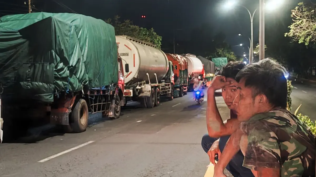 ANTRE PANJANG: Sejumlah sopir memilih duduk-duduk di median jalan pantura, Kota Pasuruan sambil menunggu antrean solar di SPBU Karangketug, Kota Pasuruan, Kamis malam (25/6). (Mokhamad Zubaidillah/ Radar Bromo)