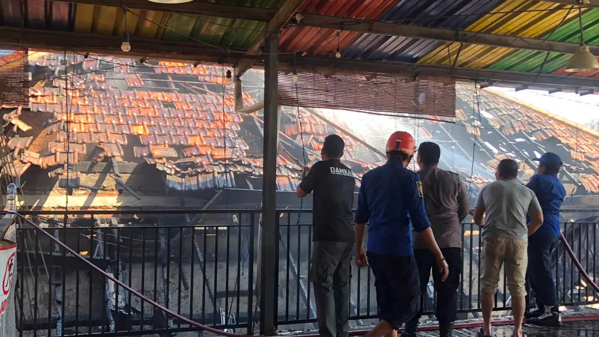 SEMPROT: Petugas Damkar Satpol PP Kota Probolinggo menyemprot bagian atap bangunan sebuah jasa pengiriman paket yang terbakar di dekat Stasiun Probolinggo, Kota Probolinggo, Minggu (28/6) pagi. sejumlah genting bangunan dibongkar agar air bisa masuk. (Inneke Agustin/ Radar Bromo)