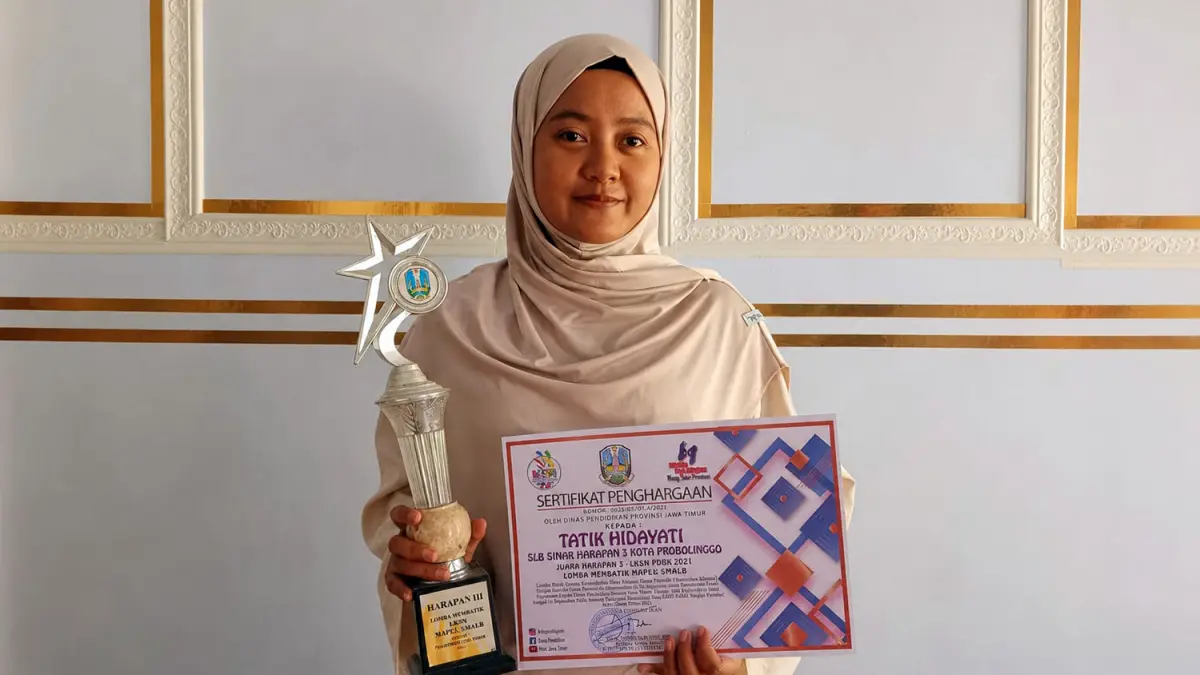 MENANG: Alumni SLB Sinar Harapan 3, Tatik Hidayati menunjukkan piala dan sertifikat Juara Harapan 3 LKSN PDBK 2021 Cabang Lomba Membatik Tingkat Provinsi Jawa Timur.
