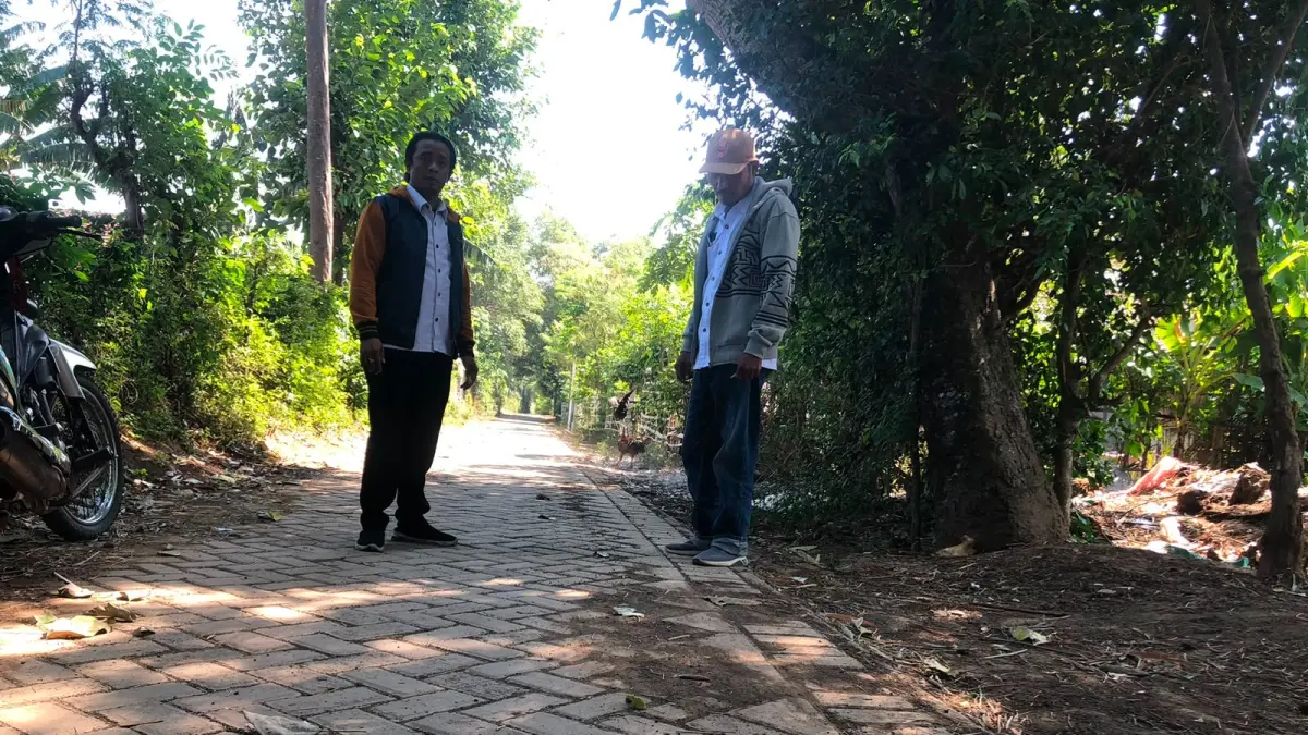 NYAMAN: Kasi Pelayanan Desa Pohsangit Lor Nemoh (kanan) bersama Kepala Dusun Kolor Abdur Rohman melintas di jalan Dusun Kelor, Desa Pohsangit Lor, yang baru rampung dipaving. NNEKE AGUSTIN/JAWA POS RADAR BROMO