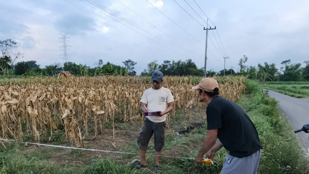 PERSIAPAN: Kasi Pelayanan Desa Pohsangit Lor Nemoh (kanan) bersama Kepala Dusun Kolor Abdur Rohman membantu proses pengukuran tanah yang akan dilakukan PTSL di Desa Pohsangit Lor.