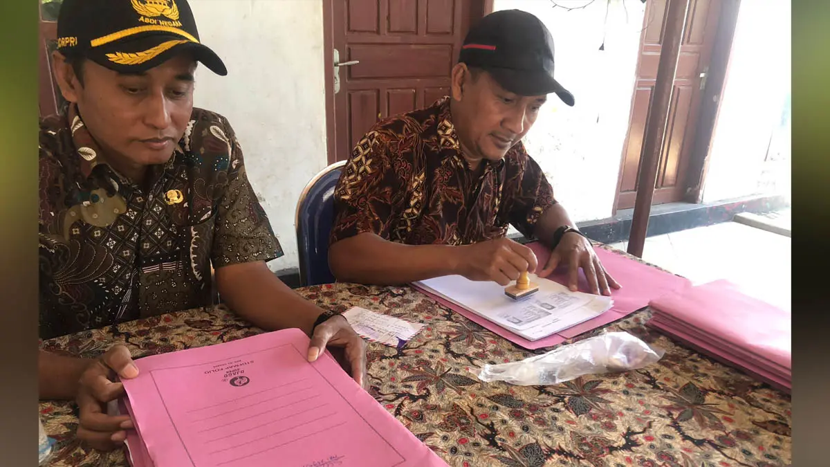 LEGAL: Sekretaris Desa Pohsangit Tengah, Suyono (kiri) saat membantu mengurus berkas milik warga yang hendak ikut program Pendaftaran Tanah Sistematis Lengkap tahun ini. (Foto: Inneke Agustin/Jawa Pos Radar Bromo)