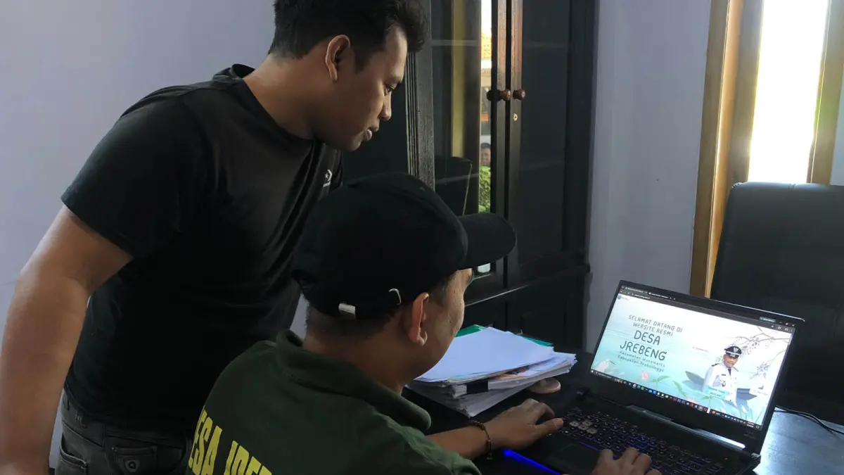 DIGITALISASI: Operator Desa Jrebeng, Fikri Agung Pangestu (kiri) dan Sekretaris Desa Jrebeng, Sodik saat mengakses website Desa Jrebeng, Kecamatan Wonomerto, Kabupaten Probolinggo. (Foto: Inneke Agustin/Jawa Pos Radar Bromo)