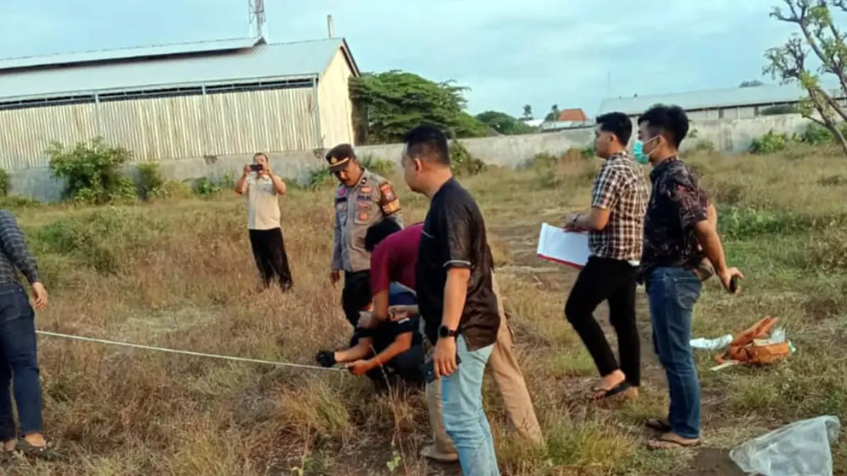 Petugas saat melakukan olah TKP penemuan mayat lelaki tanpa identitas di lahan kosong dekat Pantai Permata Pilang, Probolinggo. Pada jenazah itu didapati sejumlah luka diduga dari benda tajam. 