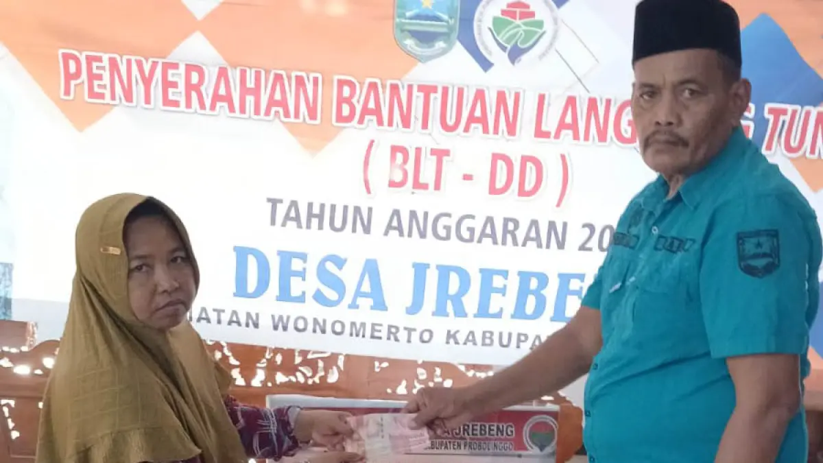 SENANG: Kepala Desa Jrebeng, Ruslan saat menyalurkan BLT DD pada salah satu warganya. (Foto: Inneke Agustin/Jawa Pos Radar Bromo)