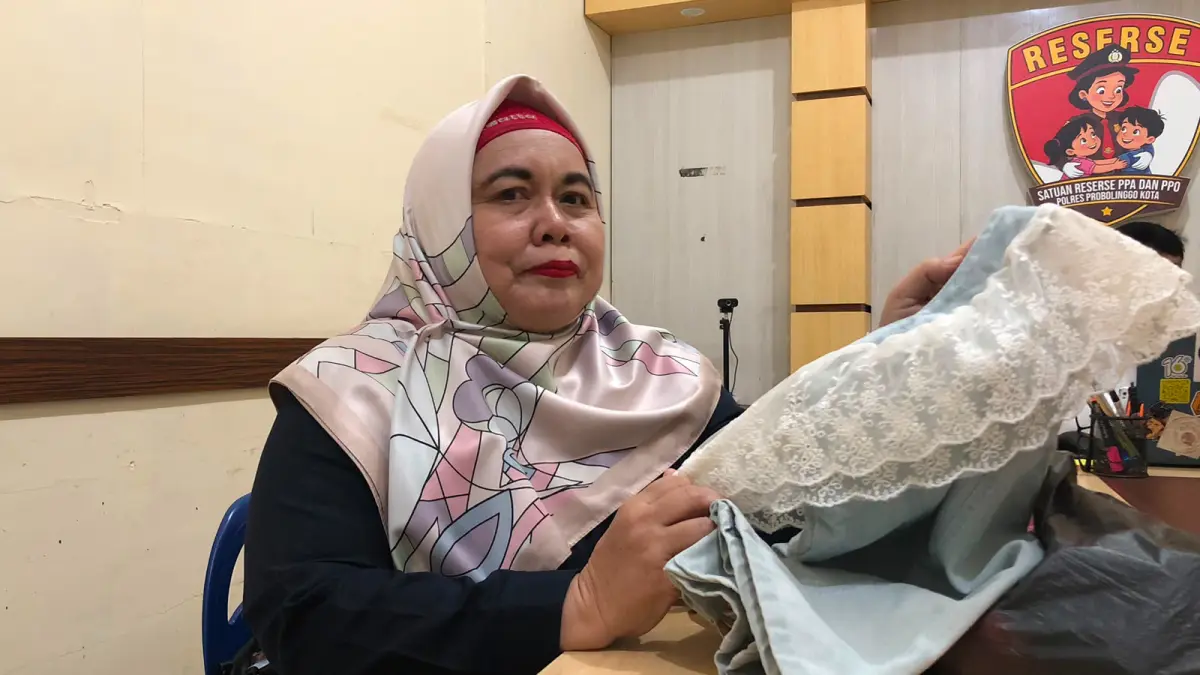 ALAT BUKTI: Salah seorang kuasa hukum korban, Siti Zuroidah menunjukkan baju milik korban yang diduga dikenakan saat dicabuli terlapor, Senin (13/7). (INNEKE AGUSTIN/JAWA POS RADAR BROMO)