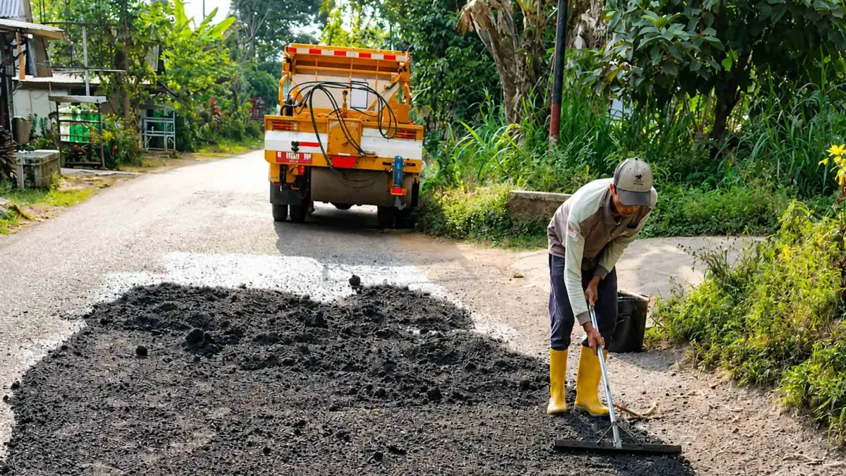 TAMBAL SULAM: Seorang pekerja memperbaiki jalan rusak di wilayah Kecamatan Krucil, Kabupaten Probolinggo. (ISTIMEWA)