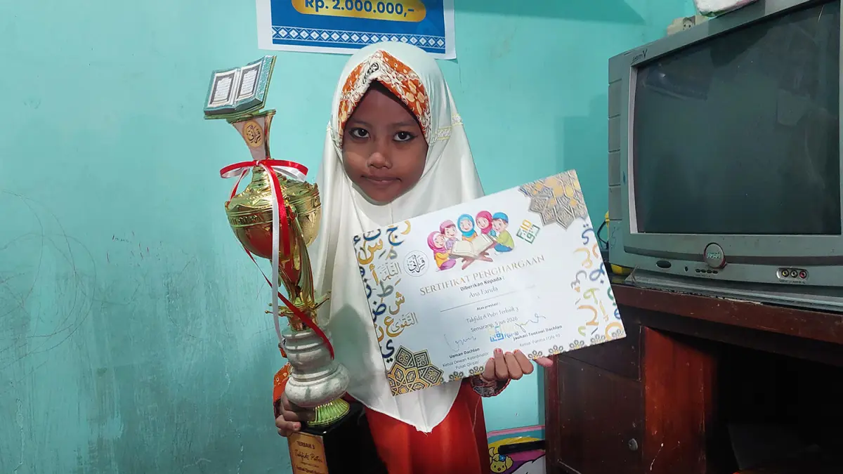 Ana Farida berpose bareng trofi yang diraihnya. (Arif Mashudi/ Radar Bromo)