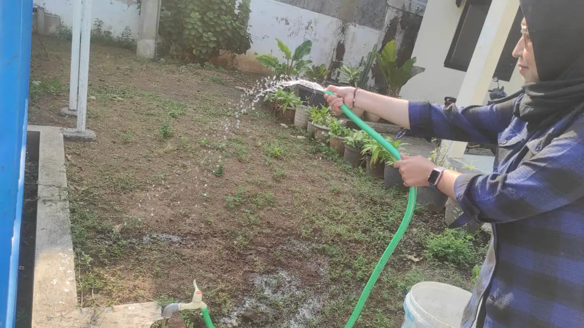 SIRAM: Pelanggan Perumdam Tirta Umbulan di Kota Pasuruan menyiram lahan halamannya. Perumdam menargetkan bisa menambah ribuan pelanggan. (Foto: Fandi Armanto/Jawa Pos Radar Bromo)
