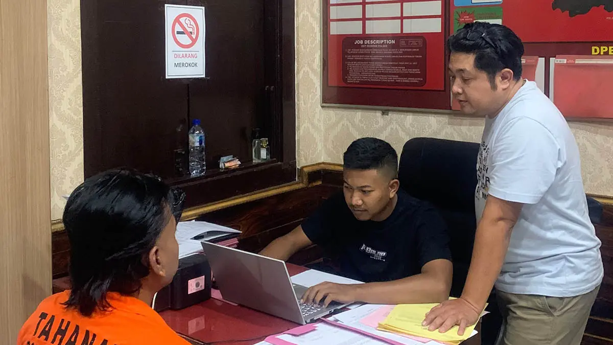 TERSANGKA: MZ (baju oranye), terduga pelaku tindak pidana penipuan dan penggelapan saat diperiksa penyidik. (Foto: Polsek Prigen for Jawa Pos Radar Bromo)