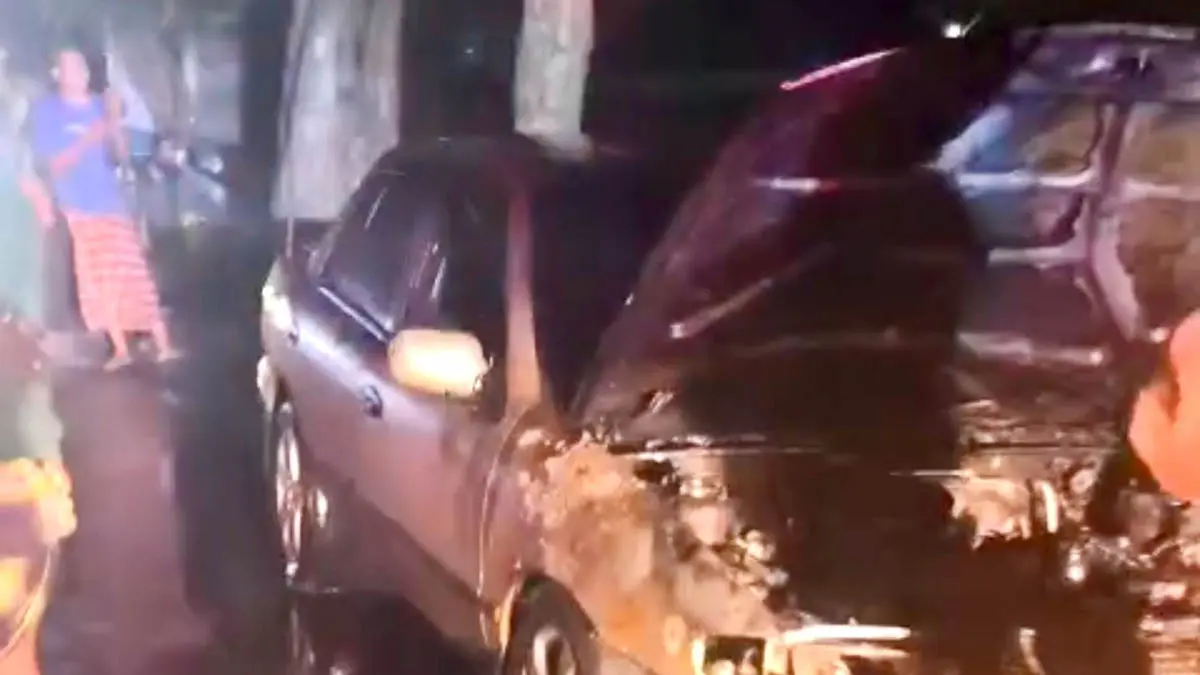 TERBAKAR BAGIAN DEPAN: Petugas Damkar Kabupaten Probolinggo memadamkan api dari mobil sedan milik Samsudin di tepi jalan pantura Desa Kebonagung, Kecamatan Kraksaan. (Foto : Damkar for Jawa Pos Radar Bromo)