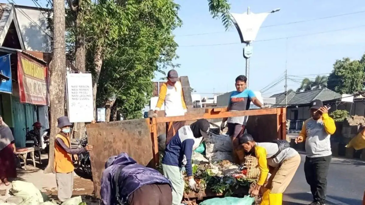SAMPAH RUMAH TANGGA: Petugas DLH mengangkut sampah di saluran tersier di Kelurahan Patokan, Kecamatan Kraksaan. (Foto: Istimewa)