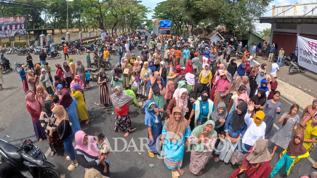 Ratusan warga Alastlogo, Lekok yang didominasi emak-emak saat memblokade jalur pantura depan Makolatmar Grati, melumpuhkan jalur pantura Surabaya-Banyuwangi, Kamis (23/7). Aksi itu buntut protes peluru nyasar ke rumah warga. (Mokhamad Zubaidillah/ Radar Bromo)