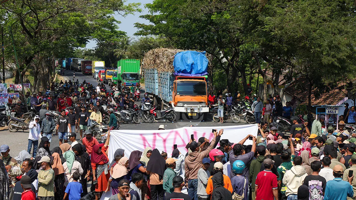 TUTUP TOTAL: Aksi ratusan warga menutup jalan nasional di ruas Pasuruan-Probolinggo Kamis (23/7) siang. Ini menjadi bentuk protes atas insiden peluru nyasar yang mengenai rumah warga. (Foto: Mokhammad Zubaidillah/Jawa Pos Radar Bromo)