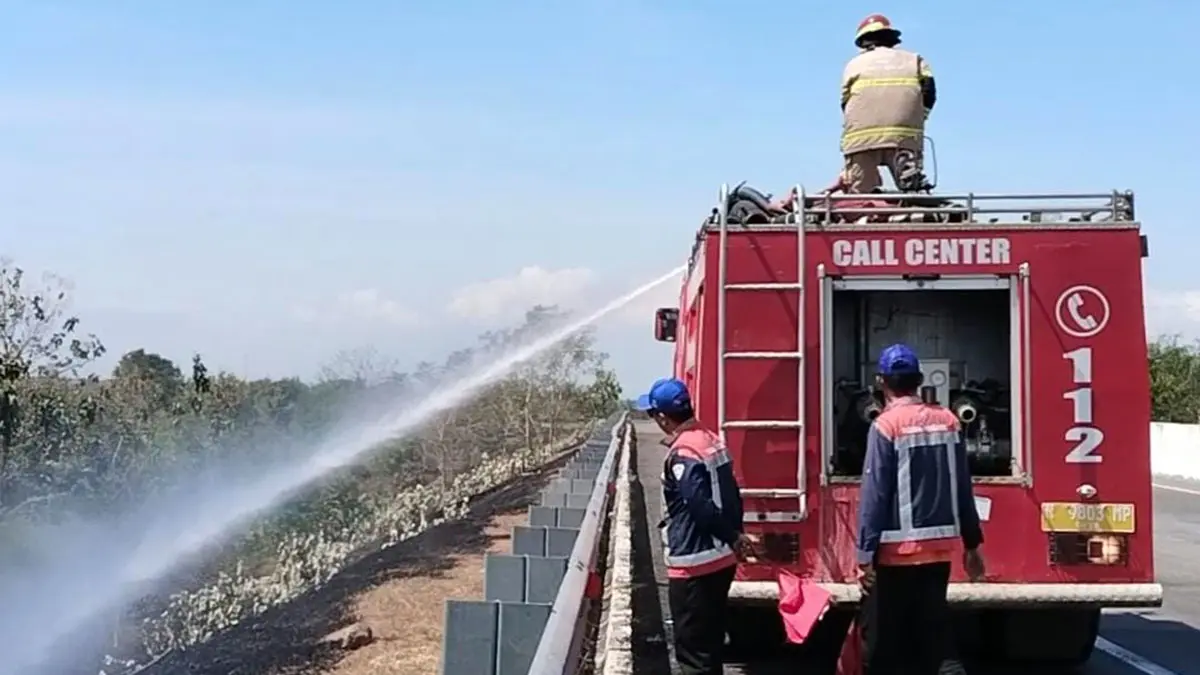 Petugas Damkar saat menyemprot lahan yang terbakar di sisi tol Paspro, (24/7)