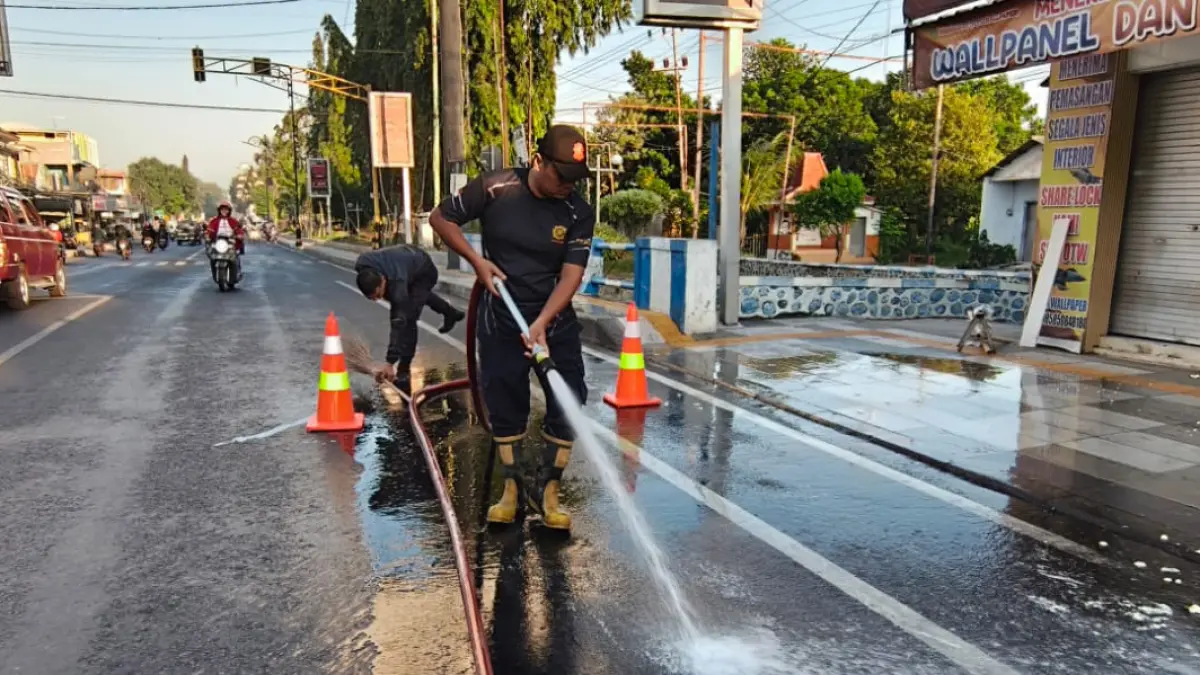 BERSIH: Tim Damkar Satpol PP Kota Probolinggo membersihkan tumpahan tahu di Jalan Raya Soekarno Hatta, Kota Probolinggo, Minggu (26/7) pagi.&nbsp;(DAMKAR SATPOL PP KOTA PROBOLINGGO FOR JAWA POS RADAR BROMO)