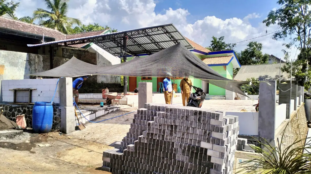 TERTATA: Sejumlah pekerja membangun pagar dan memasang paving di halaman gedung Posyandu di RT 2/RW 1, Dusun Krajan. (Achmad Arianto/Jawa Pos Radar Bromo)