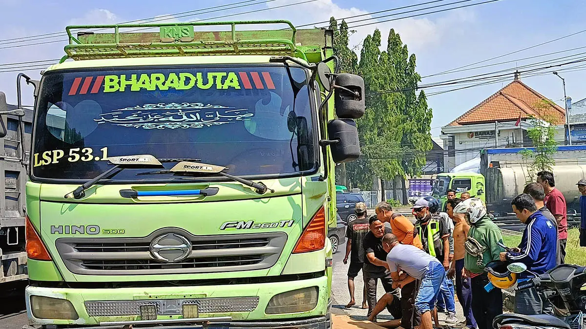 TKP: Pengendara motor yang terjatuh dan tertabrak dump truk di bundaran Apollo Gempol. Pengendara terluka parah dan masih berada di bawah kolong dump truk. (Foto: Istimewa)