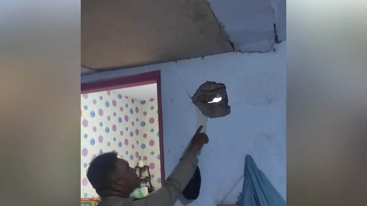 DI SINI: Petugas kepolisian Polsek Tongas menunjukkan lubang bekas lemparan bondet di rumah MR, 38, warga Desa Curahtulis, Kecamatan Tongas, Kabupaten Probolinggo, Jumat (31/7). (Foto: Polsek Tongas for Jawa Pos Radar Bromo)