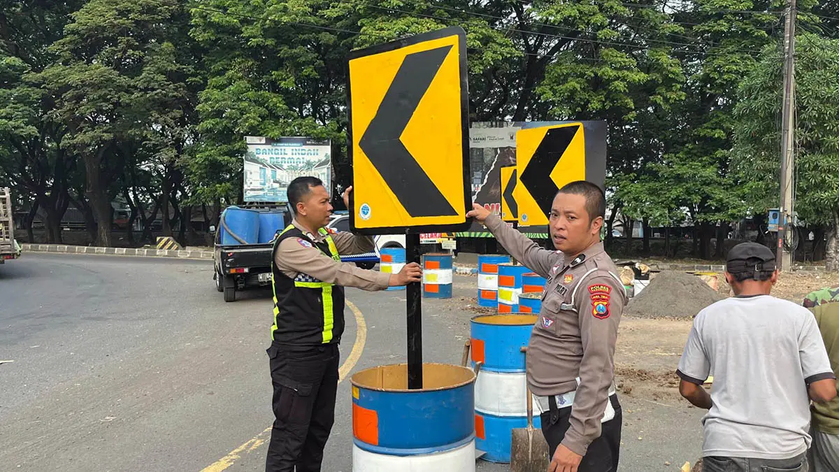 PASANGI RAMBU: Petugas Satlantas Polres Pasuruan saat memasang rambu tambahan di kawasan Bundaran Apollo Gempol. Langkah ini dilakukan, untuk meminimalisir kecelakaan. (Satlantas Polres Pasuruan)
