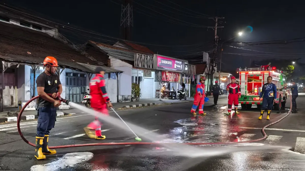 GOSOK: Tim Damkar Satpol PP Kota Probolinggo membersihkan tumpahan solar di Simpang Empat Ketapang, Kecamatan Kademangan, Sabtu (1/8) malam. (DAMKAR SATPOL PP KOTA PROBOLINGGO FOR JAWA POS RADAR BROMO)
