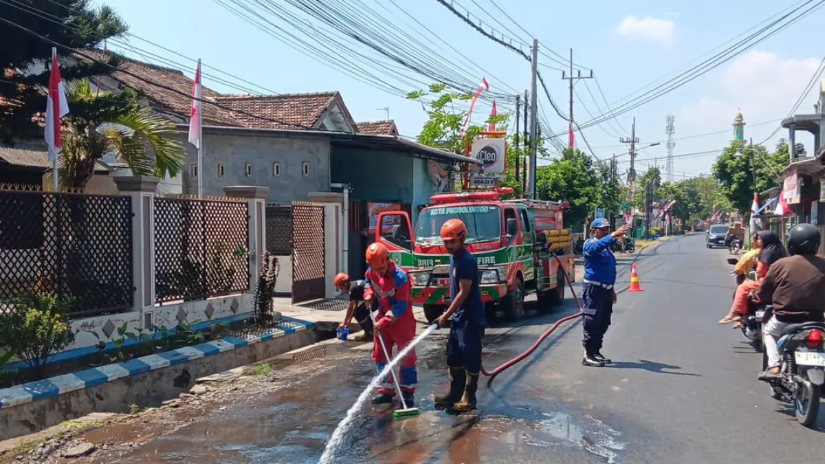SEMPROT: Tim Damkar Satpol PP Kota Probolinggo membersihkan ceceran solar di tikungan Jalan Slamet Riyadi, Kelurahan/Kecamatan Kanigaran, Rabu (5/8). (DAMKAR SATPOL PP KOTA PROBOLINGGO FOR JAWA POS RADAR BROMO)