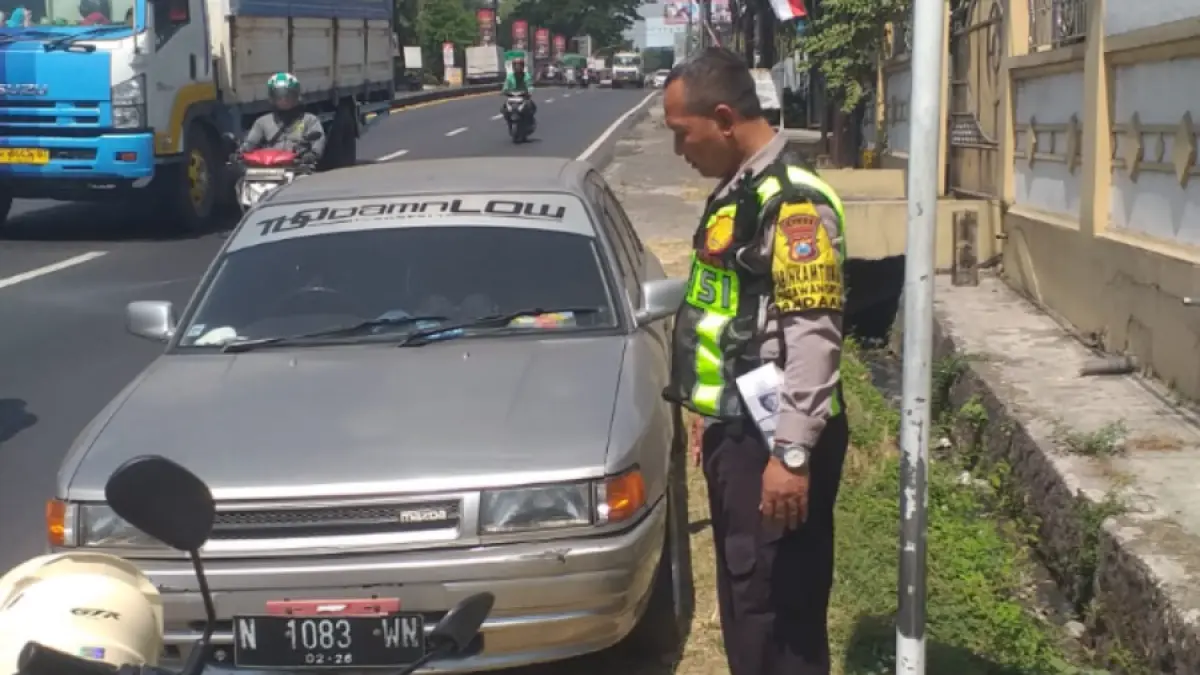 DIAMANKAN: Anggota Polsek Pandaan memeriksa satu unit mobil sedan Mazda bernopol N 1083 VN, yang telantar di bahu jalan nasional ruas Malang–Surabaya, Kelurahan Petungasri, Kecamatan Pandaan, Kamis (6/8). (Polsek Pandaan for Jawa Pos Radar Bromo)