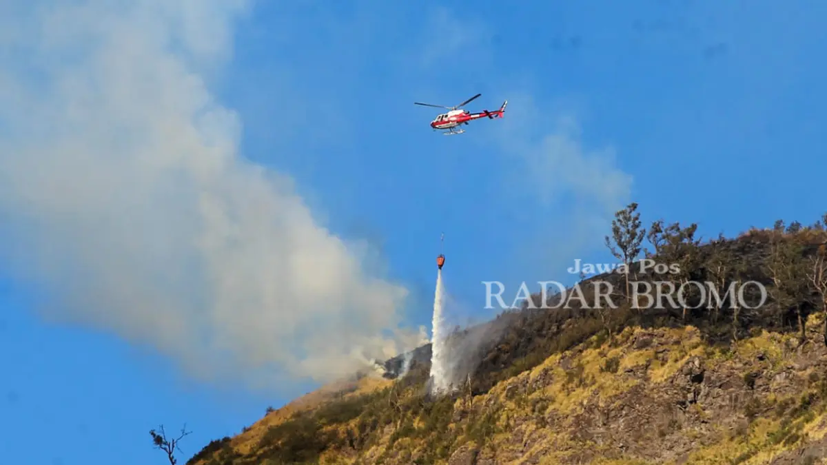 WATER BOMBING: Helikopter milik BNPB saat melakukan pemadaman dengan metode water boombing di area Pusung Jantur, Desa Sariwani, Kecamatan Sukapura, Kabupaten Probolinggo, kemarin (7/8) sore. Kobaran api tampak bergerak ke arah P-30. (Mokhamad Zubaidillah/ Radar Bromo)