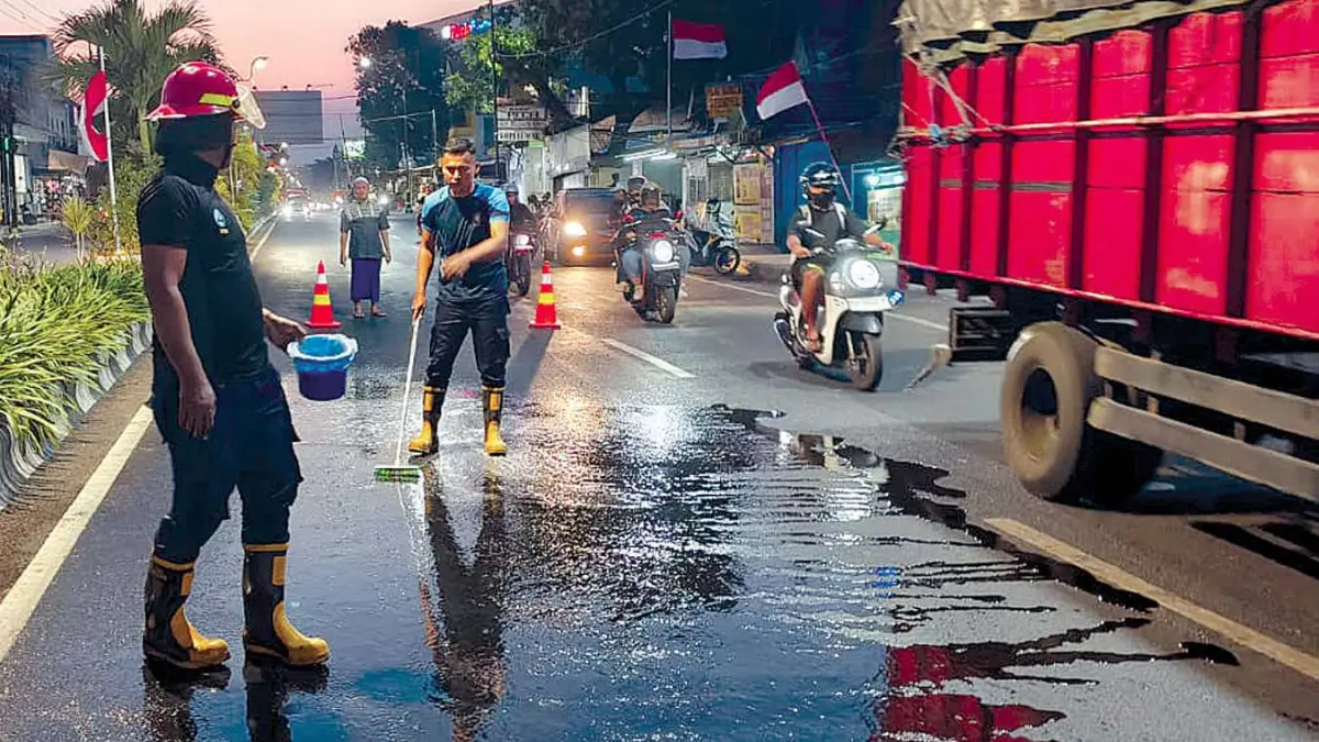 SEMPROT: Tim Damkar Satpol PP Kota Probolinggo membersihkan ceceran solar di Jalan Panglima Soedirman, Kelurahan Jati, Kota Probolinggo, Minggu (9/8) petang.&nbsp;(DAMKAR SATPOL PP KOTA PROBOLINGGO FOR JAWA POS RADAR BROMO)