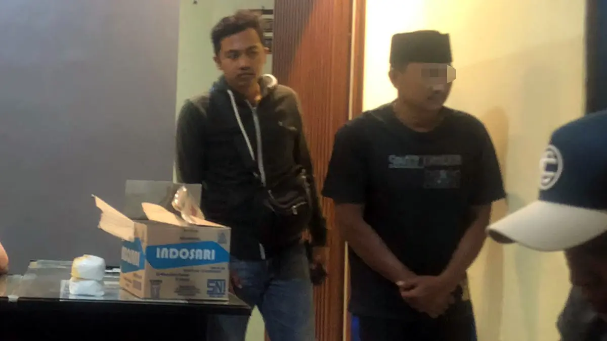 DITETAPKAN TERSANGKA: KUS (pakai peci) saat diamankan di Mapolsek Wonomerto, Probolinggo. (Inneke Agustin/ Radar Bromo)