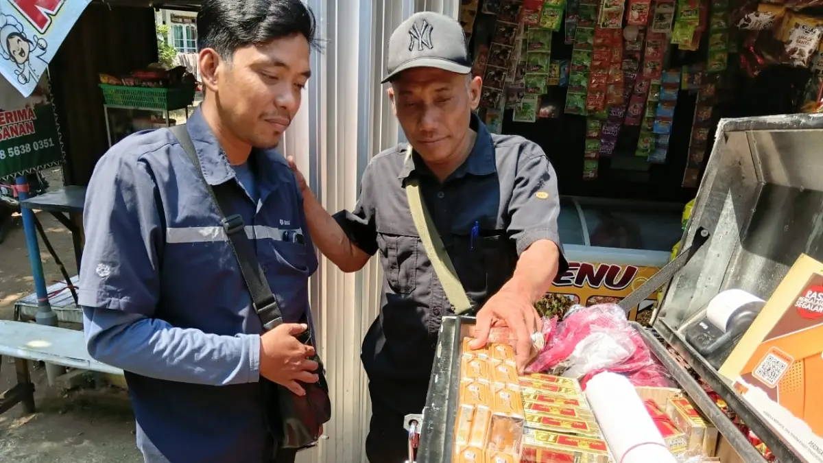 PASTIKAN LEGALITAS: Kepala Bidang Penegakan Peraturan Perundang-undangan Daerah (PPUD) Satpol PP Kabupaten Pasuruan, Suyono, memeriksa dengan teliti pita cukai pada kemasan rokok yang dijual di salah satu toko kelontong di Kabupaten Pasuruan. (Satpol PP Kabupaten Pasuruan for Jawa Pos Radar Bromo)