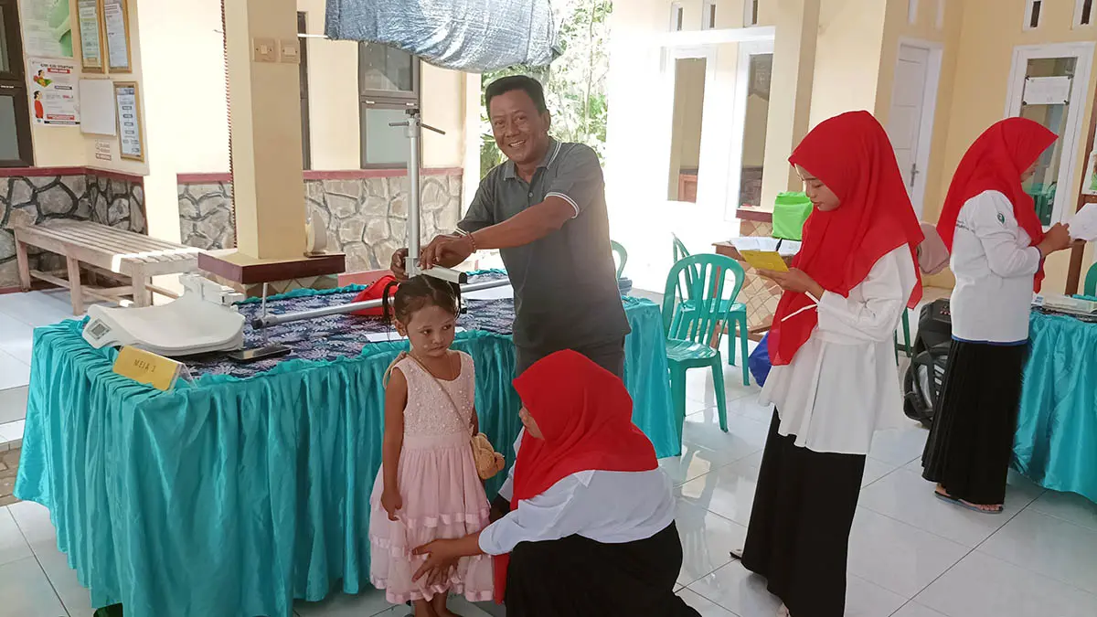 PELAYANAN: Kepala Desa Rawan Mustofa saat membersamai kegiatan posyandu di kantor desa setempat. Tepat di belakang area kantor desa ini, merupakan lokasi rawa bersejarah yang menjadi saksi bisu awal berdirinya desa sejak tahun 1835. (Agus Faiz Musleh/Radar Bromo)