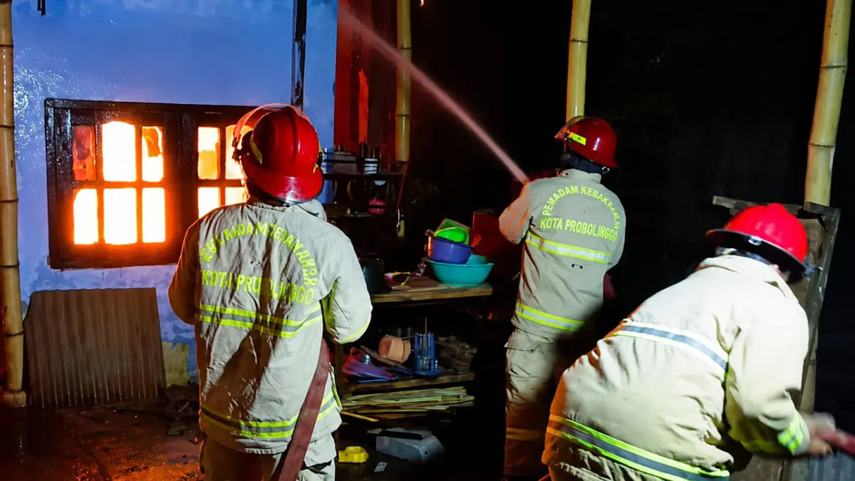 TERBAKAR: Tim Damkar Satpol PP Kota Probolinggo memadamkan api di rumah Sulistiorini, di Jalan Anggrek, Kota Probolinggo, Sabtu (15/8) malam. (DAMKAR SATPOL PP KOTA PROBOLINGGO FOR JAWA POS RADAR BROMO)