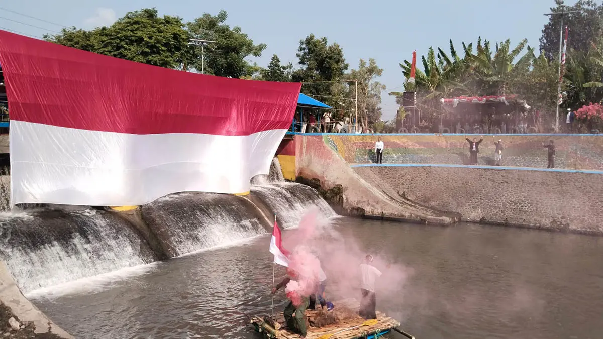 DI ATAS SUNGAI: Bendera merah putih sepanjang 17 meter yang dikibarkan di DAM Pleret. (Foto: M Busthomi/Jawa Pos Radar Bromo)