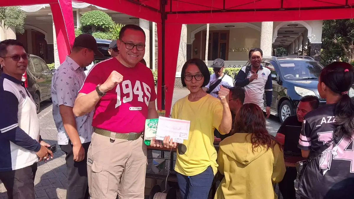 GRATIS: Kepala BPPKAD Kota Probolinggo Pujo Agung Satrio berfoto bersama pengunjung CFD yang membayar PBB dengan QRIS dan mendapatkan gula atau minyak goreng gratis, Minggu (16/8).&nbsp;(Istimewa)
