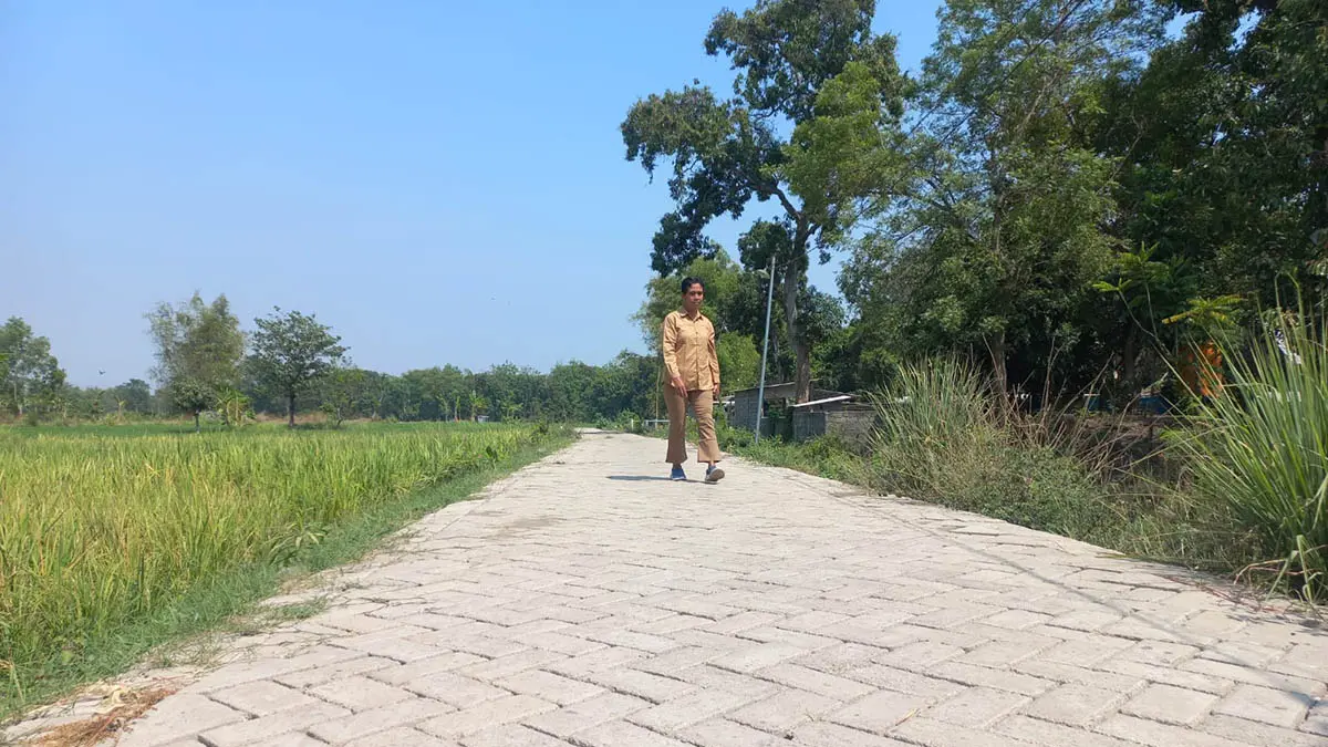 NYAMAN: Bendahara Desa Tongas Wetan, Jijin Giharsusi saat melintasi ruas jalan di Dusun Krajan yang telah dilakukan pavingisasi. (Foto: Inneke Agustin/Jawa Pos Radar Bromo)