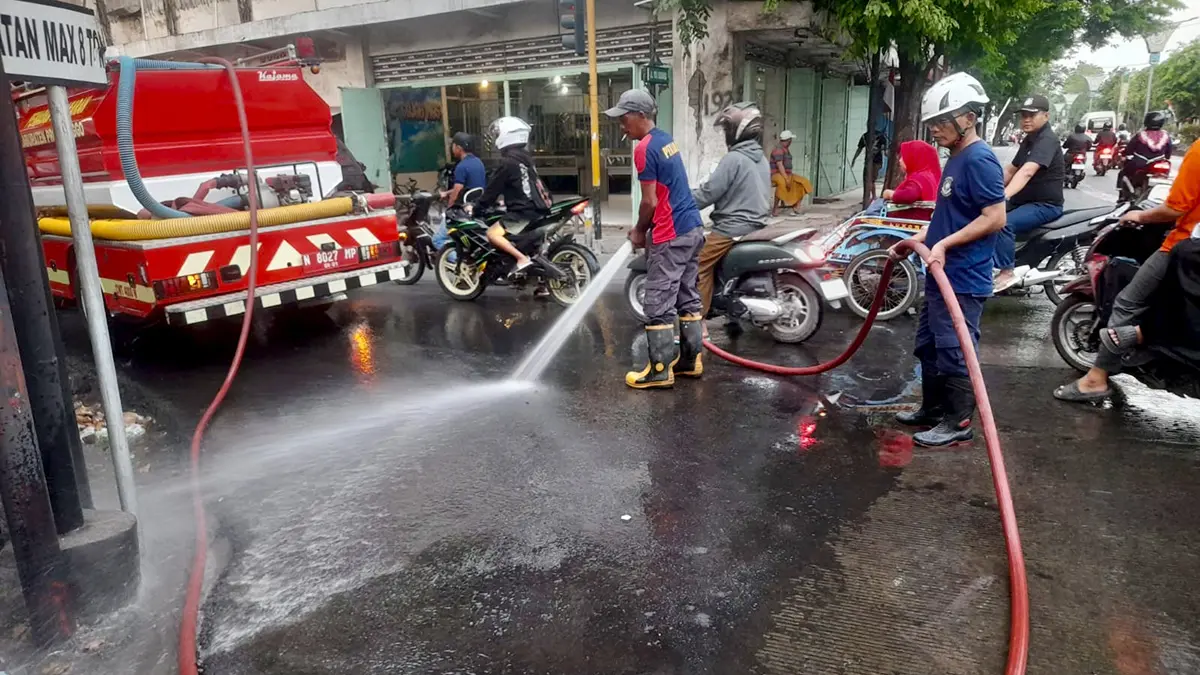 LICIN: Tim Damkar Kabupaten Probolinggo membersihkan tumpahan solar di Jalan Panglima Sudirman, Kecamatan Kraksaan, Senin (17/8) sore.&nbsp;(DAMKAR FOR JAWA POS RADAR BROMO)