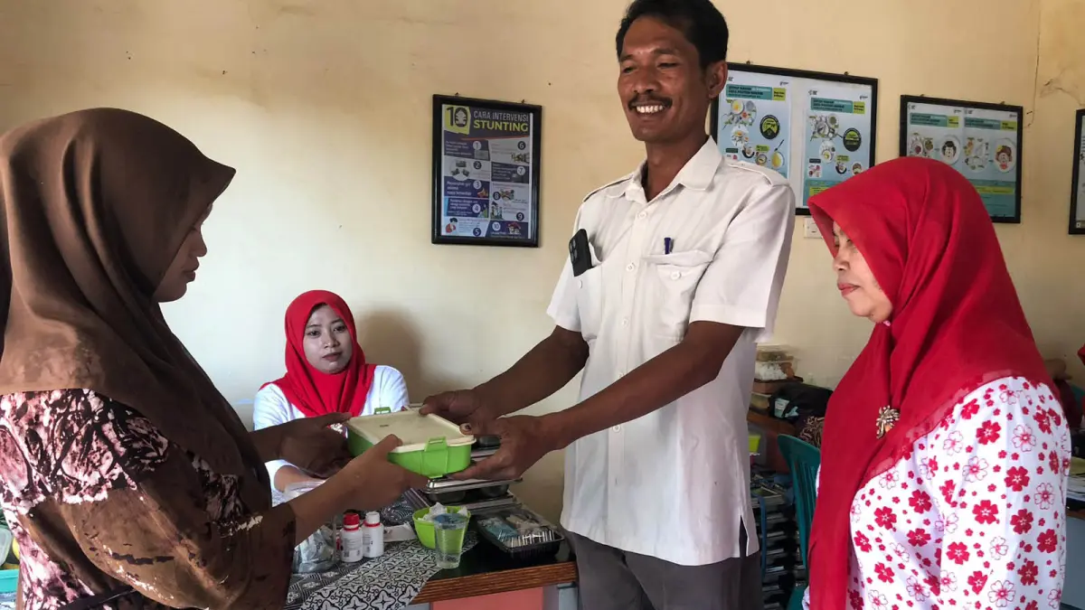 SENANG: Kepala Desa Dungun, Muhammad Kasim memberikan MBG pada salah satu warganya di Desa Dungun, Kecamatan Tongas. (Foto: Inneke Agustin/Jawa Pos Radar Bromo)