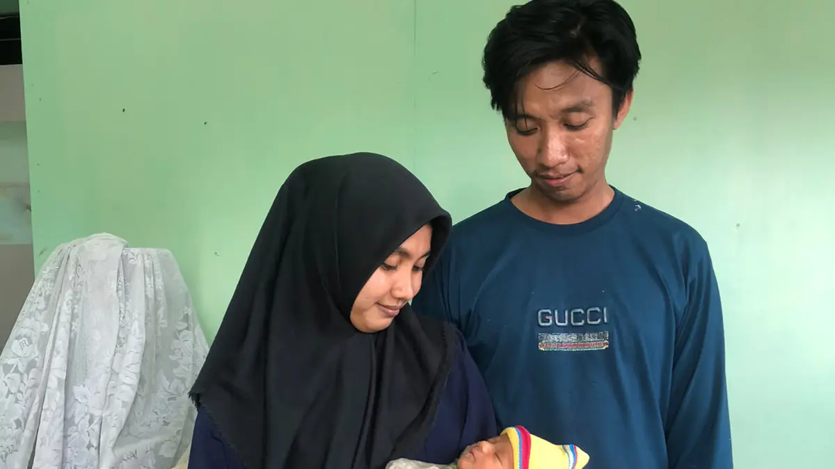 SAYANG: Makrup bersama istrinya Afidayani, menggendong bayi laki-laki di Puskesmas Curahtulis, Selasa (18/8). (DOK. JAWA POS RADAR BROMO)