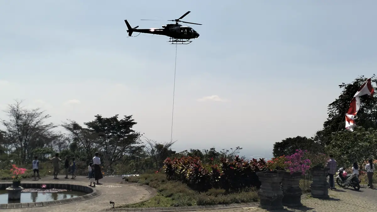 PENASARAN: Warga menyaksikan dari dekat saat helikopter mengambil air dari kolam Kaliandra untuk pemadaman di lereng Gunung Arjuno dengan water bombing, Rabu (26/8). (Rizal Syatori/ Radar Bromo)