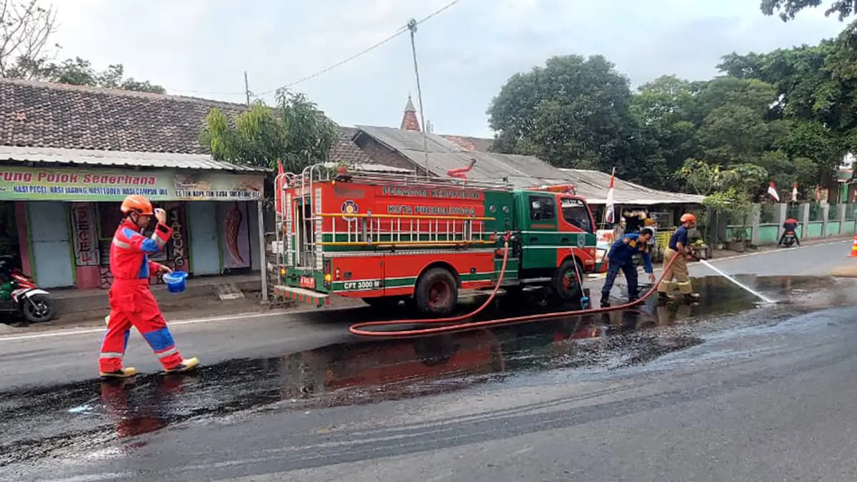 SEMPROT: Tim Damkar Satpol PP Kota Probolinggo membersihkan ceceran solar di Pertigaan Jalan Semeru, Kelurahan Triwung Kidul, Kota Probolinggo, Jumat (28/8) sore. (DAMKAR SATPOL PP KOTA PROBOLINGGO FOR JAWA POS RADAR BROMO)