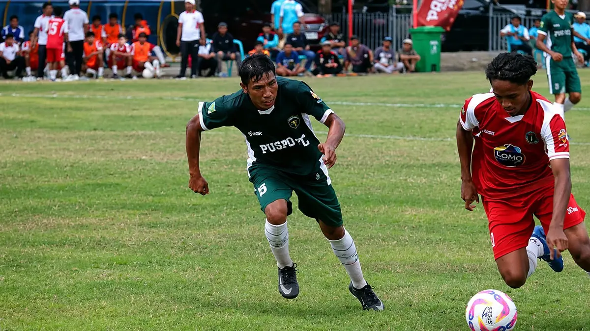 KETAT: Stiker Pandaan FC Yoshua (kostum merah) dikawal Fendi, pemain Puspo FC dalam laga perdana Bupati Cup 2026 Pasuruan Superleague. Pandaan berhasil meraih tiga poin. (Fajrul Falach/ Magang Radar Bromo)