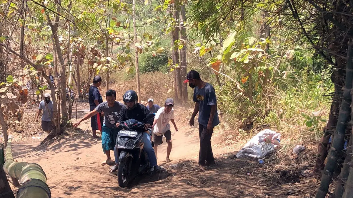 DORONG: Sejumlah warga membantu pengendara motor yang melintasi jalan alternatif di Desa Paras, Tegalsiwalan. Jalan ini dibuka warga selama jembatan Curah Bubur ditutup.