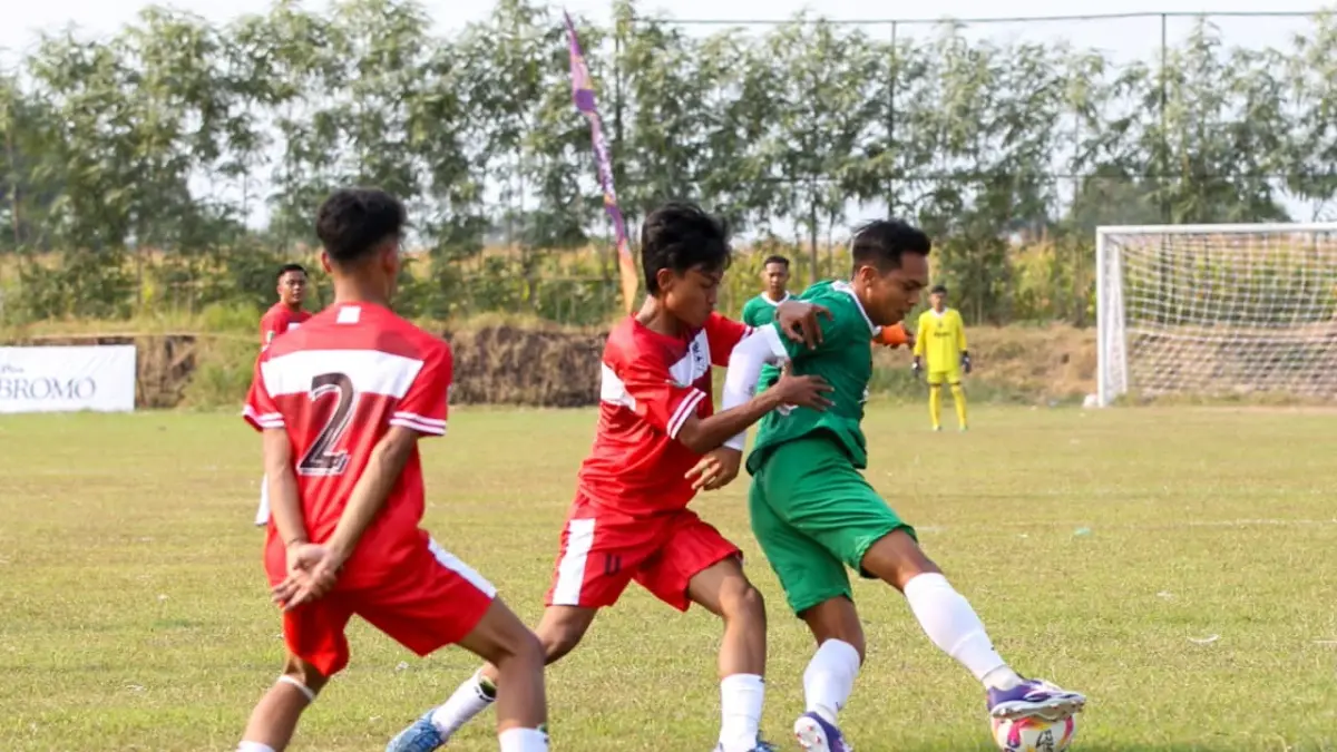 TAK BERKUTIK: Striker Bangil FC Ricko Hardiansyah (jersey hijau) dikawal pemain Priogen FC dalam laga Grup A bupati Cup 2026 Pasuruan Superleague di Lapangan Kebotohan, Kraton, Jumat (4/9) sore,